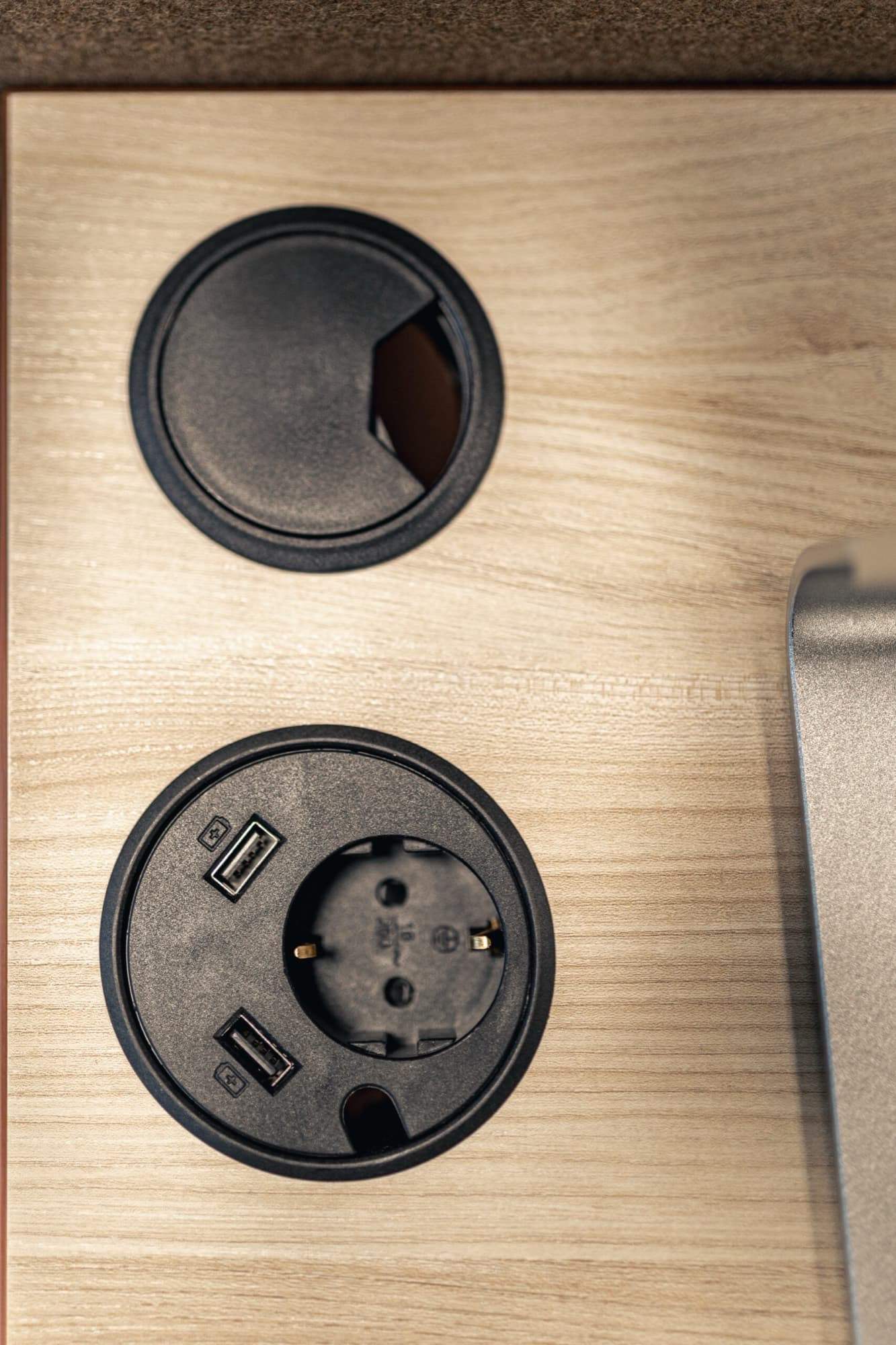 Detalj av skrivbordets kabelgenomföring och ett infällt uttag med två USB-portar.